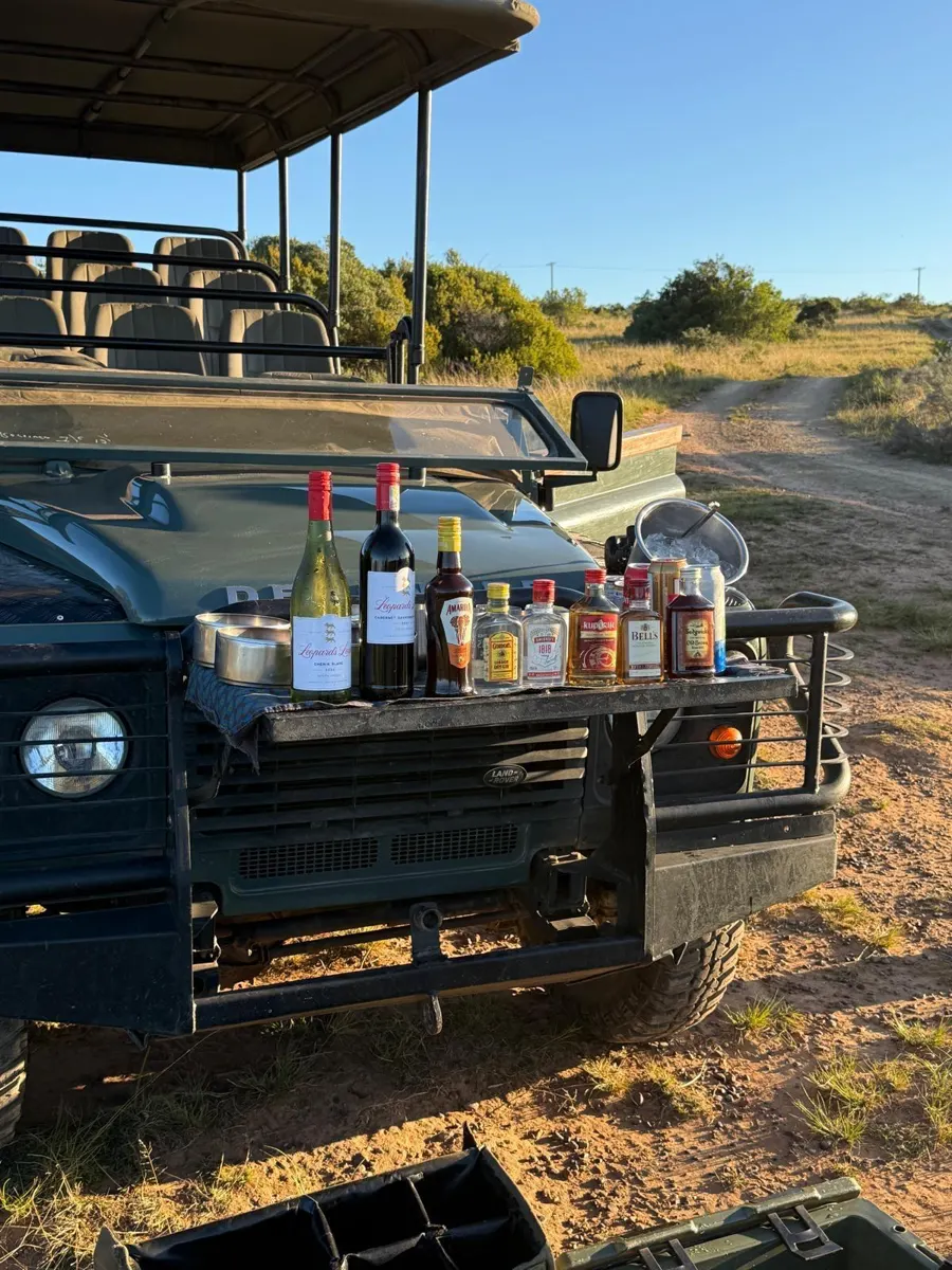 Sundowner-drankjes op de motorkap van een safarijeep in de bush